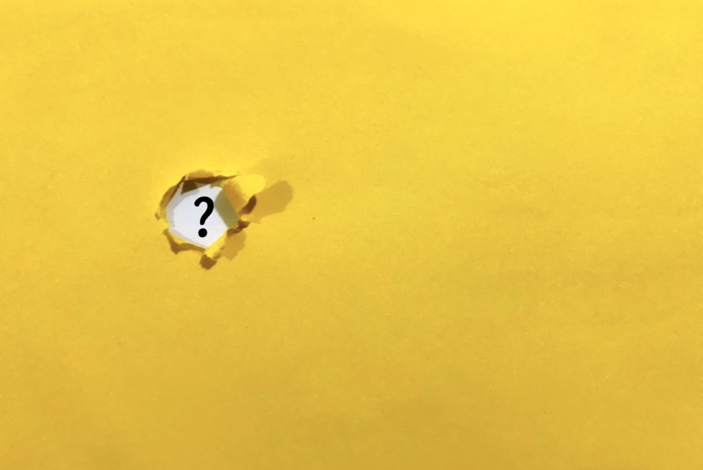 Yellow ripped background with question mark visible through rip